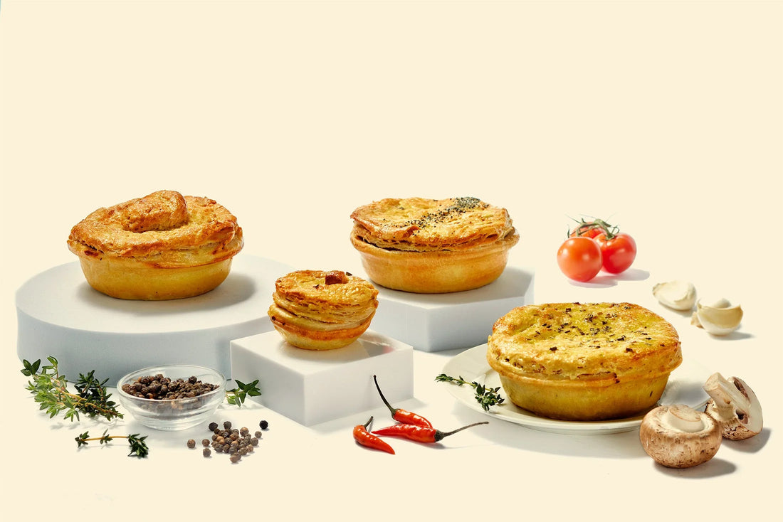 Collection of large and small savory pies on a counter with ingredients